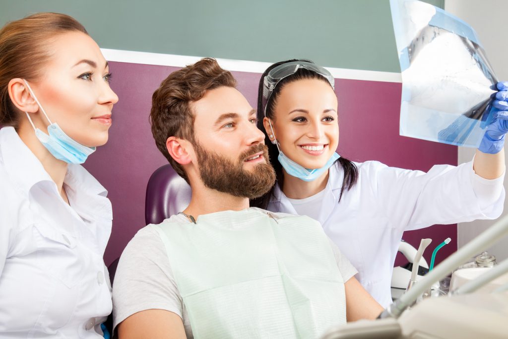 Dentist shows a patient x-ray of teeth.